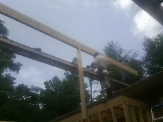 Carpenter setting a ridge beam over a new addition frame — Ice Dam Removal by Roofing Brothers in Delhi