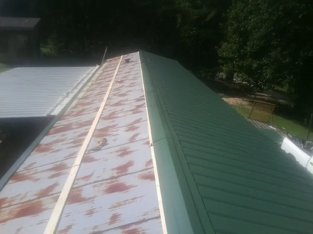 Old rusted panels beside newly installed green metal roofing — Wind Damage Roof Repair by Roofing Brothers in Delhi