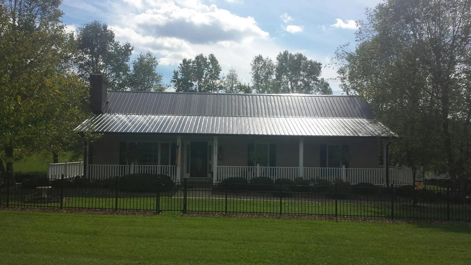 Gray metal roof on a brick ranch with a full width front porch — Gutter Guard Installation work by our crew in Delhi