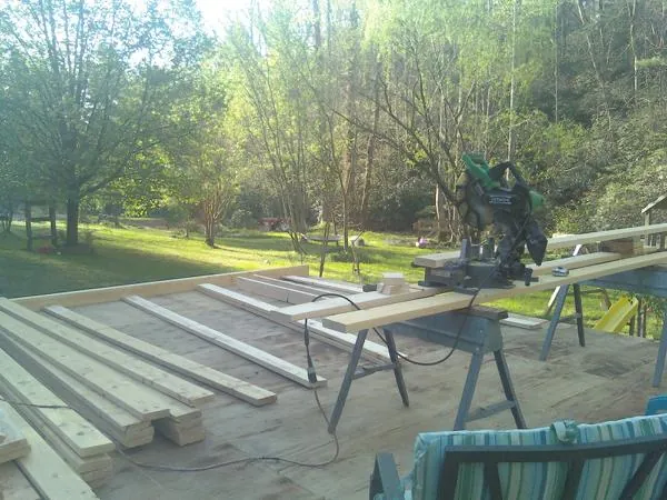 Miter saw and framing lumber on a deck under construction in Delhi